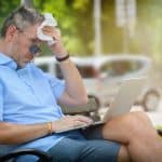 Man suffers from heat while working with laptop